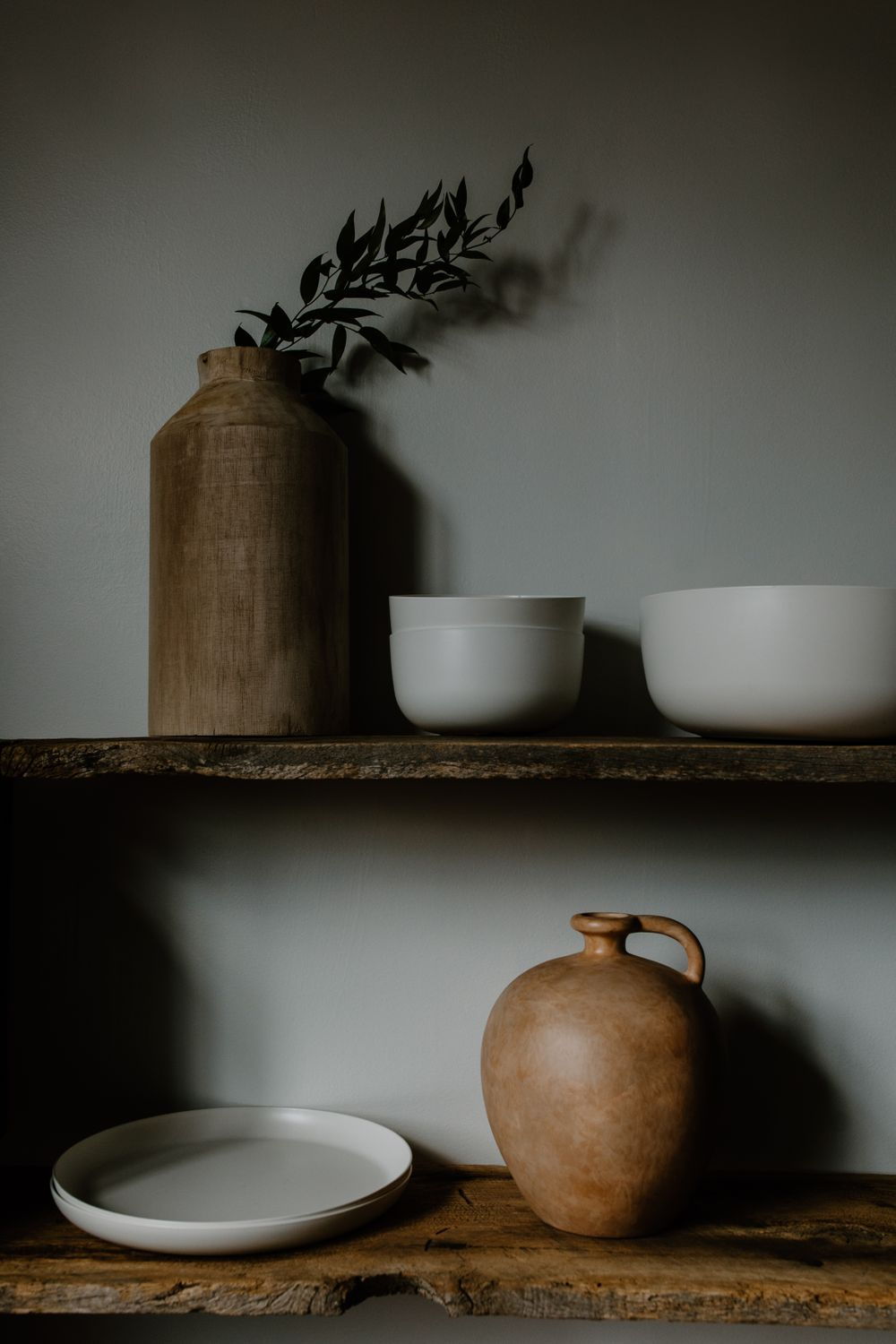 Ceramiczne naczynia na dębowej półce w półmroku